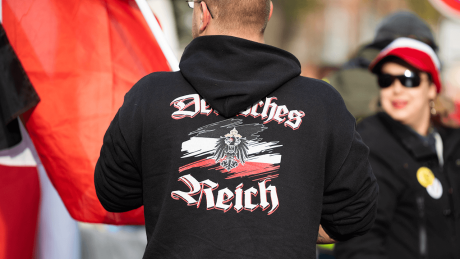 Ein Mann trägt einen Pullover mit dem Aufdruck "Deutsches Reich" bei einer Demonstration von Reichsbürgern © dpa/Christophe Gateau