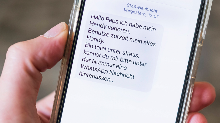 Hand hält ein Mobiltelefon mit einer Nachricht auf dem Display, die der Beginn eines Messengerbetrugsfall ist © IMAGO / Guido Schiefer