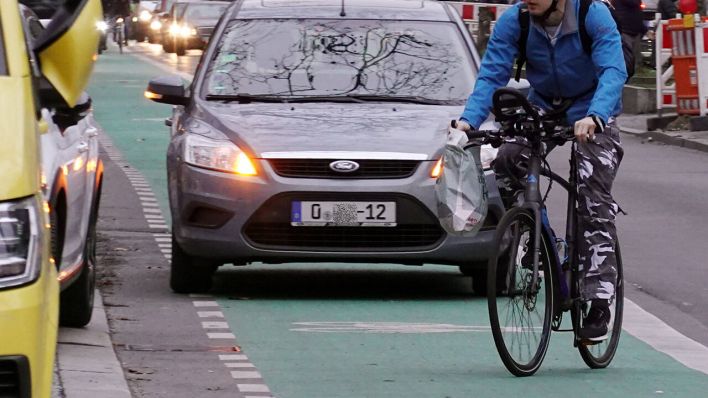 Ein Radfahrer umfährt in Berlin auf einem grün gekennzeichneten Fahrradweg ein widerrechtlich parkendes Auto eines Diplomaten © imago images/Frank Sorge