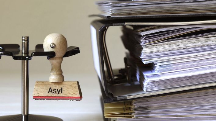 Ein Stempel mit dem Schriftzug "Asyl" neben einem Stapel Aktenordner © imago/Bernhard Classen