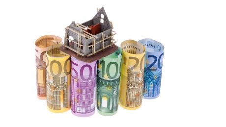 Geldscheine mit einem Modell eines Haus-Rohbaus © imago images/McPHOTO