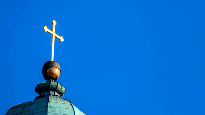 Ein Kreuz auf einem Kirchturm © imago images/McPHOTO