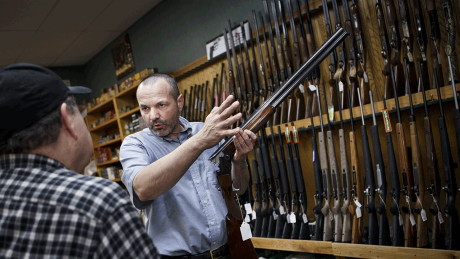 Ein Waffenhändler führt einem Kunden ein Gewehr vor © imago/ZUMA Press