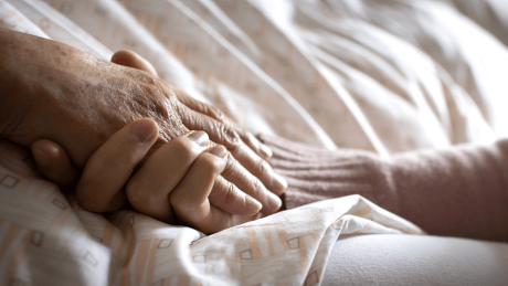 Eine Altenpflegerin hält die Hand einer Frau © imago images/photothek