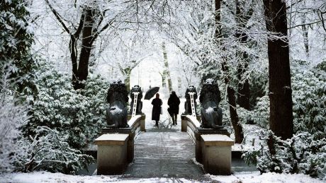 Menschen spazieren durch den verschneiten Tiergarten