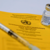 Symbolbild einer Impfdosis und Ampulle der Firma BioNTech/Pfizer auf einem internationelen Impfausweis © imago images/Political-Moments