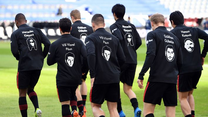 Bundesliga, Eintracht Frankfurt - Bayern München am 20.02.2021: Frankfurts Spieler tragen die Bilder und Namen der Opfer des Terroranschlags von Hanau vor einem Jahr beim Aufwärmen auf der Trainingsjacke. ©dpa/Arne Dedert