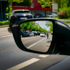 Eine Radfahrerin ist im Rückspiegel eines Autos zu sehen