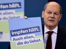 Bundeskanzler Olaf Scholz (SPD) präsentiert ein Plakat für eine neue Impfkampagne © Hannibal Hanschke/POOL AP/dpa