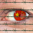 Symbolbild Menschenrechte in China: Auge einer Frau mit chinesischer Flagge im Augapfel blickt durch einen Stacheldraht © imago images/Ralph Peters