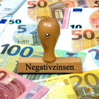 Auf Geldscheinen steht ein Stempel mit dem Schriftzug Negativzinsen © imago images/Steinach