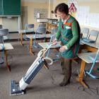 Eine Reinigungskraft saugt in einem Klassenraum (Symbolbild) © imago images/photothek