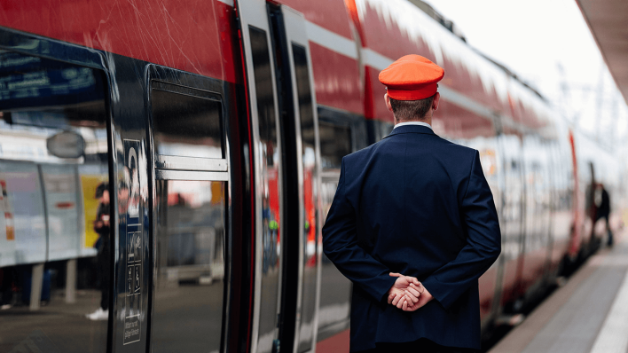 Ein Schaffner steht an einer Regionalbahn © imago images/Future Image