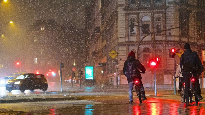 Radfahrer*innen stehen bei Regen an einer roten Ampel