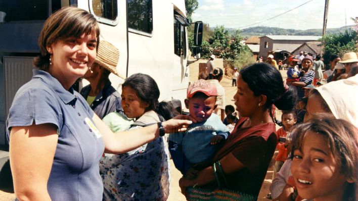 Tanja Hock steht mit Frauen und Kindern vor ihrem Hebammen-Mobil in Antananarivo, Madagaskar (undatiertes Archivfoto) © picture alliance/dpa | Klaus Heimer