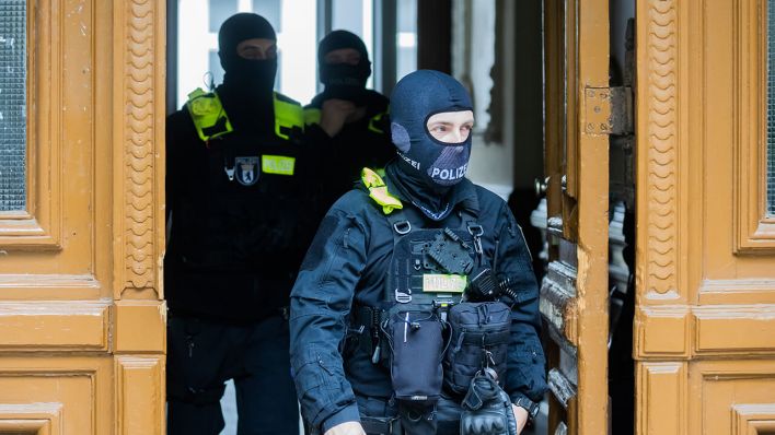 Polizisten kommen bei einer Hausdurchsuchung in Berlin-Kreuzberg aus einem Gebäude © dpa/Christoph Soeder
