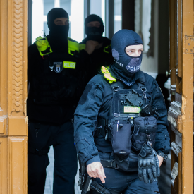 Razzia gegen "Letzte Generation": Polizisten kommen bei einer Hausdurchsuchung in Berlin-Kreuzberg aus einem Gebäude © dpa/Christoph Soeder