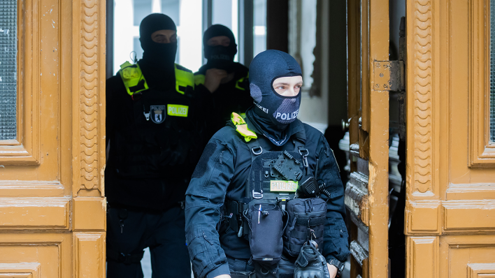 Razzia gegen "Letzte Generation": Polizisten kommen bei einer Hausdurchsuchung in Berlin-Kreuzberg aus einem Gebäude © dpa/Christoph Soeder