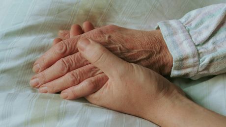 Einer alten Frau wird im Bett die Hand gehalten © imago/photothek/Ute Grabowsky