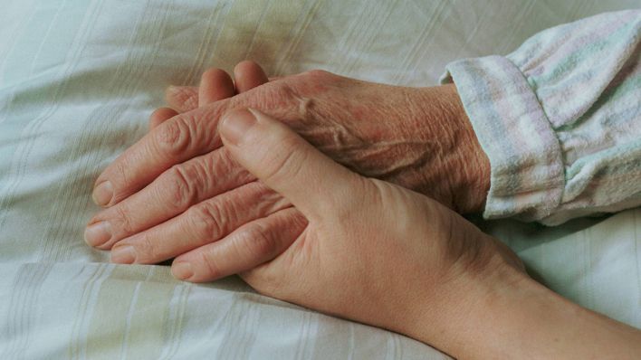 Einer alten Frau wird im Bett die Hand gehalten © imago/photothek/Ute Grabowsky