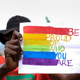 Ein ugandischer Mann hält ein Pride-Bild mit Regenbogenfarben in der Hand © picture alliance / ASSOCIATED PRESS