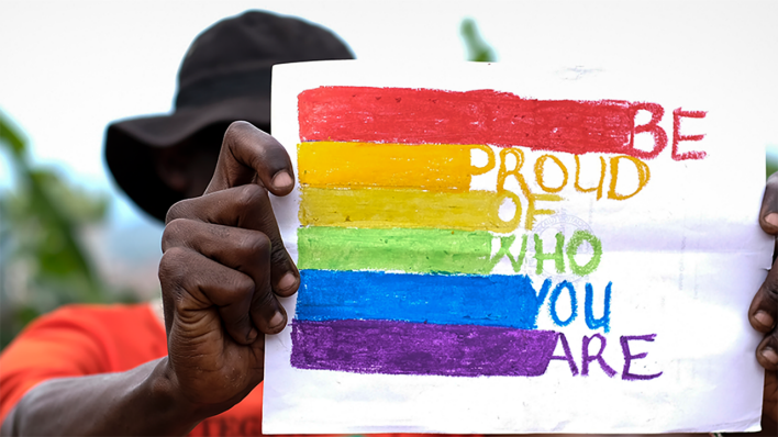 Ein ugandischer Mann hält ein Pride-Bild mit Regenbogenfarben in der Hand © picture alliance / ASSOCIATED PRESS