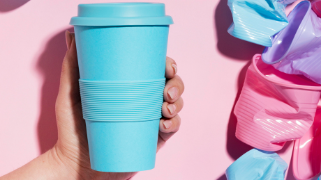 Eine Hand hält einen Mehrwegbecher, daneben Einwegbecher © IMAGO / ingimage