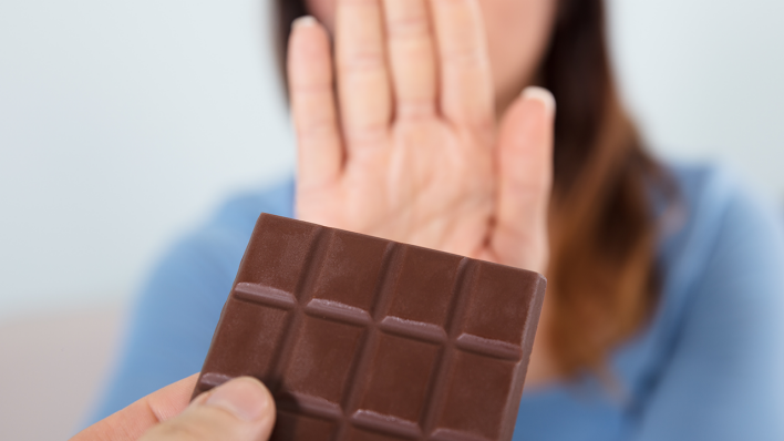 Eine Frau lehnt eine Tafel Schokolade ab © IMAGO / Panthermedia