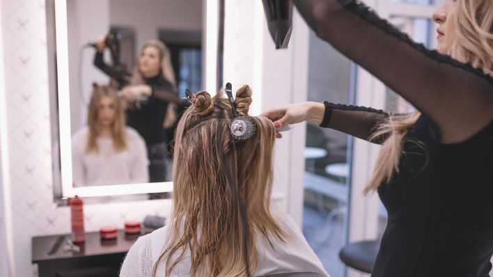 Eine Friseurin fönt einer Kundin die Haare © imago images/imagebroker