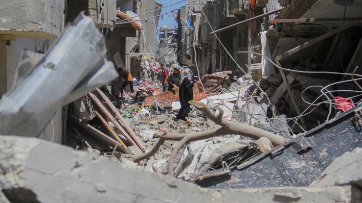 Zahlreiche Menschen stehen am 31.05.2024 zwischen zerstörten Häusern in Gaza © imago images/Middle East Images