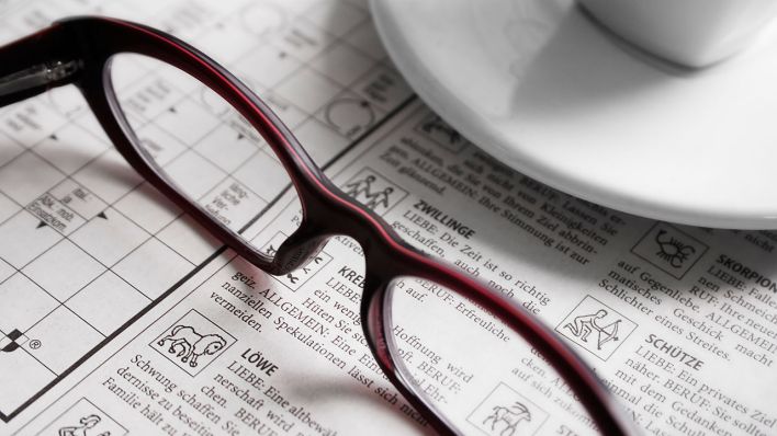 Eine Brille liegt auf einer Zeitung mit Horoskop © imago images/Panthermedia