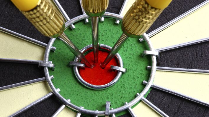 Wurfpfeile stecken mitten im Ziel, dem Bullseye, auf einer Dartscheibe © imago images/Jochen Tack