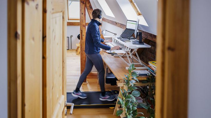 Eine Frau geht während der Arbeit zu Hause im Home Office an ihrem Schreibtisch auf einem Walking Pad © IMAGO/photothek