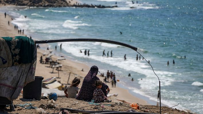 Eine Mutter sitzt mit ihren Kinder am Strand im Gazastreifen © © picture alliance / ASSOCIATED PRESS | Abdel Kareem Hana