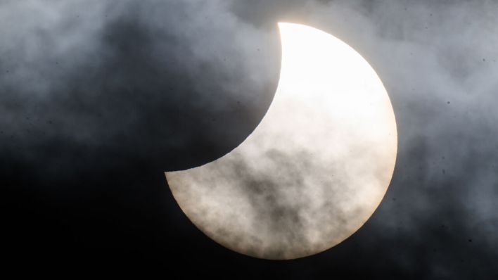 Eine partielle Sonnenfinsternis ist zwischen Wolken am Himmel zu sehen (Aufnhame vom 25.10.2022) © Julian Stratenschulte/dpa