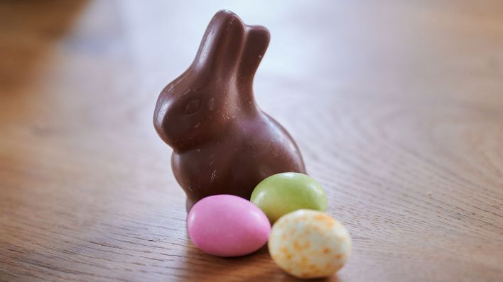 Ein ausgepackter Osterhase aus Schokolade und Schokoladeneier auf einem Tisch © dpa/Annette Riedl