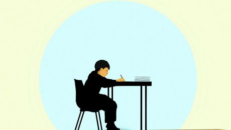 Junge schreibt etwas an einem Schreibtisch © IMAGO / Ikon Images