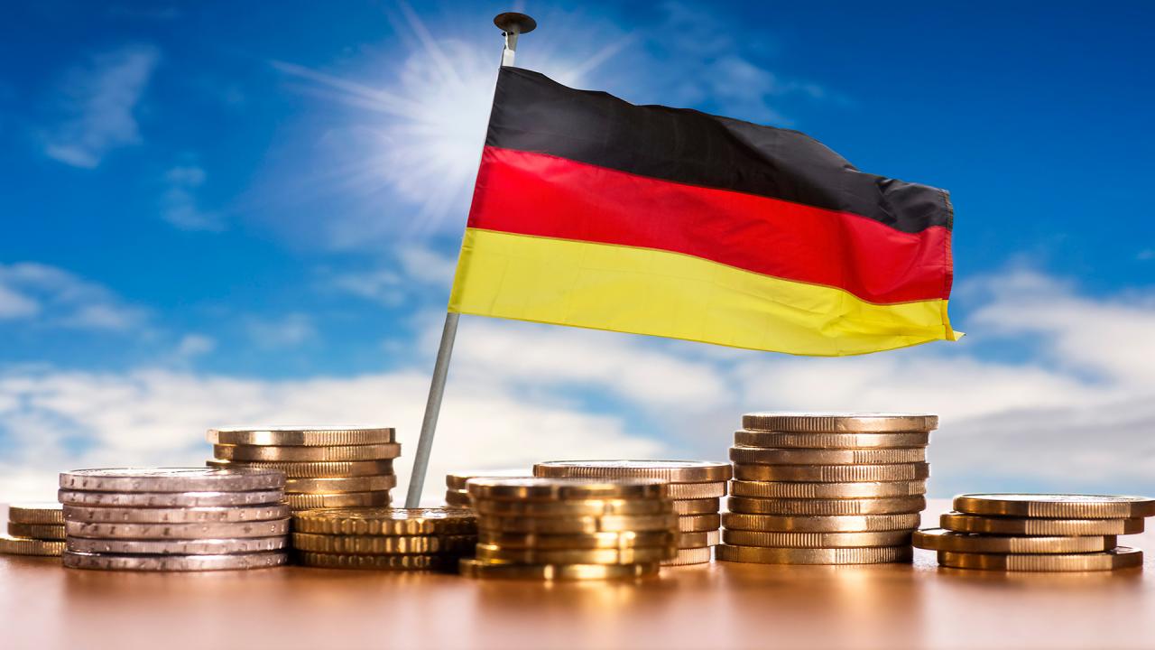 Deutsche Flagge mit Stapeln von Euro Münzen vor blauem Himmel (picture alliance / Klaus Ohlenschläger)