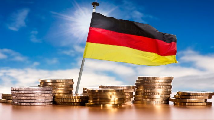 Deutsche Flagge mit Stapeln von Euro Münzen vor blauem Himmel (picture alliance / Klaus Ohlenschläger)